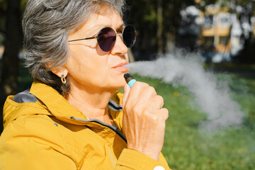 Profile portrait of elderly woman smoking modern new electronic cigarette vape, nicotine...