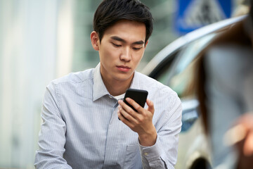 young asian business man using cellphone outdoors