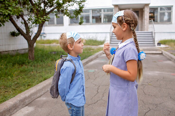 Back to school. Elementary school kids. Siblings with backpacks in medical masks talks together...