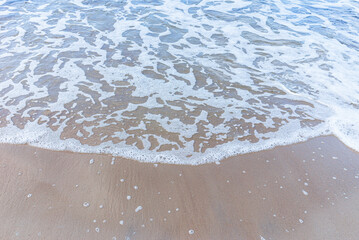 Wave of the sea on sandy beach white foam.Top view of a wave breaking on the sand at the beach. Top view,Copy space.
