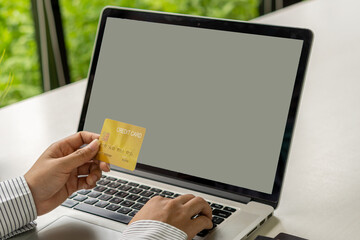 Young woman holding a credit card and using a laptop computer with a white screen Business woman working at home . online shopping, ecommerce, internet banking, money spending concept,