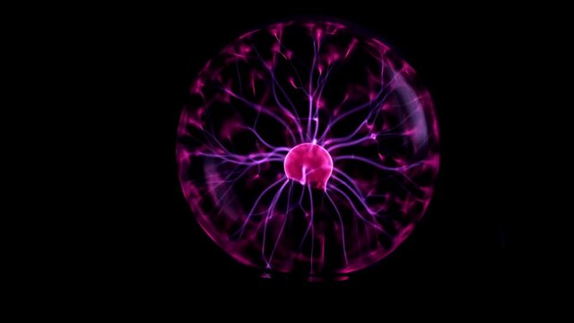 Tesla energy plasma ball lit over black background reflecting .Tesla coil - physics experiment for children .