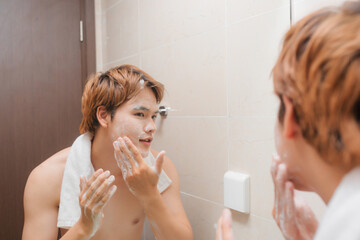 Portrait of attractive young Asian male wash his face in bathroom
