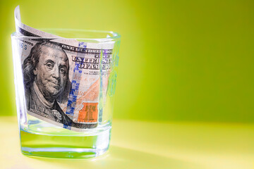 100 dollar bill in whiskey glass