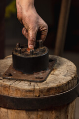 Close-up working powerful hands of male blacksmith forge an iron product in a blacksmith. Hammer, red hot metal and anvil. Concept of labor, retro professions