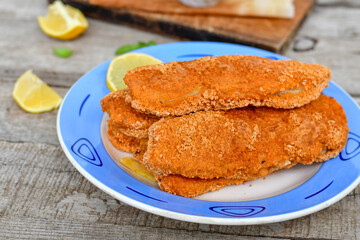  Fish and Chips/Close up of   crispy breaded  deep fried alaska pollock  fillets  with breadcrumbs served with remoulade sauce french fries  and   fresh lemons 