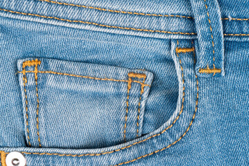 Blue jeans pocket close up. Details of jeans trousers with orange stitching