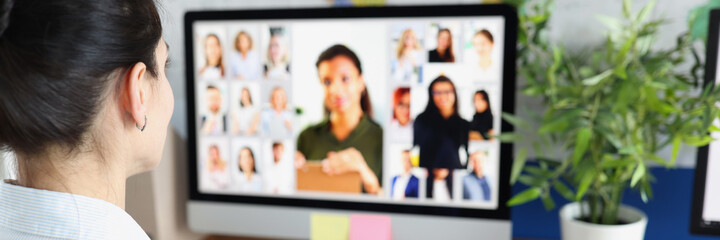 Woman communicating with group of business people via video conferencing