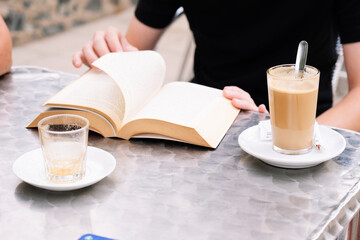 Teen boy with curly hair reading a book in a bar