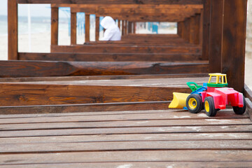 Toy tractor forgotten on empty wooden beach loungers on deserted beach