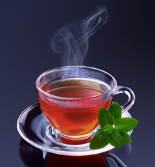 Teeglas mit dampfendem Tee und frischer Minze