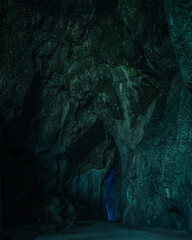 Dark cave with stalactites illuminated by green light