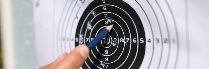 Man showing with pencil to shots on paper target closeup
