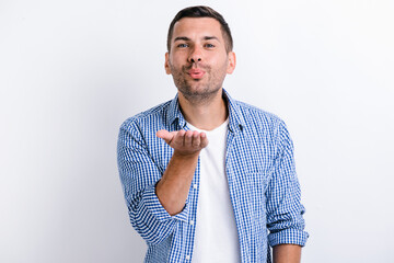 Portrait of amorous handsome brunette man holding palm up while sending air kiss at camera,...