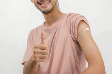 Portrait of asian young man, malel teenage attractive after getting, receive anti virus vaccine covid-19. Showing arm on bandage in casual, isolated on white background, copy space