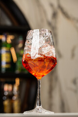Bartender preparing on the counter Aperol Spritz, a classic refreshing Italian aperitif made mixing Aperol, Prosecco and sparkling soda.