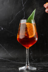 Glass of ice cold Aperol spritz cocktail served in a wine glass, decorated with slices of orange...