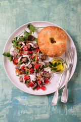 Salad with vegetables and meat on a white plate. Homemade bun.