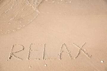 Word Relax written on sand at beach