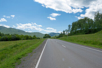 highway road and mountain peaks on the background of a blue sky with clouds
