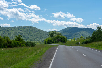 Fototapeta premium highway road and mountain peaks on the background of a blue sky with clouds