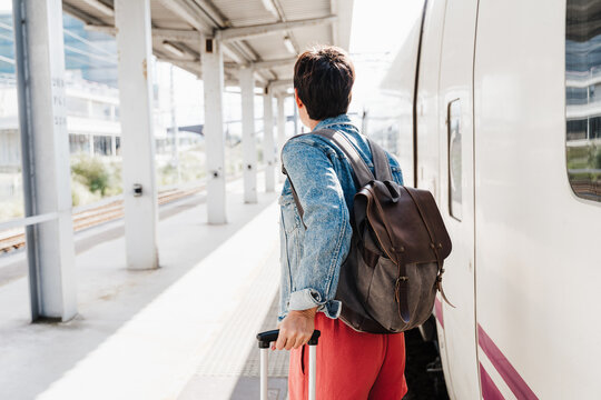 close up of backpacker caucasian woman holding luggage at train station ready to catch the train. Holding mobile phone while using app. Travel concept