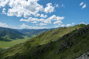 Fototapeta na wymiar mountain peaks against a blue sky with clouds and a green valley