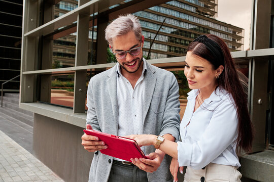 Cheerful man showing tablet to female colleague