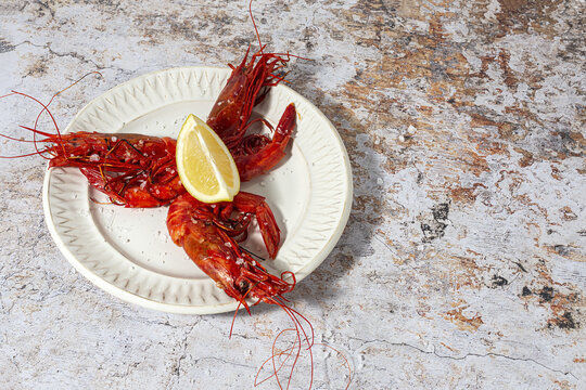 Scarlet shrimps with aromatic lemon pieces on plate