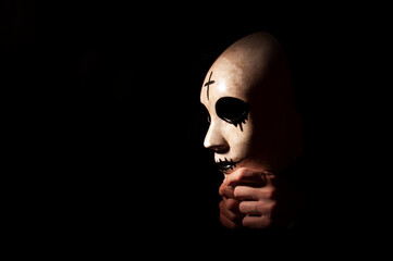Side image of mask in hand with black background. Side view of high contrast photograph. halloween concept with copyspace.