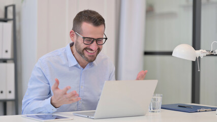 Fototapeta premium Middle Aged Man Celebrating Success while using Laptop 