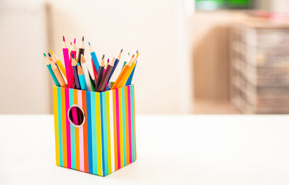 Pencils colored in a holder on student desk, blur room background. Education, back to school