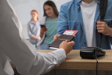 Agent giving passport with ticket to client at check-in desk in airport, closeup