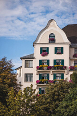 Wohnhaus mit romantisch bepflanzter Fassade bei bewölktem Himmel mit Bäumen im Vordergrund