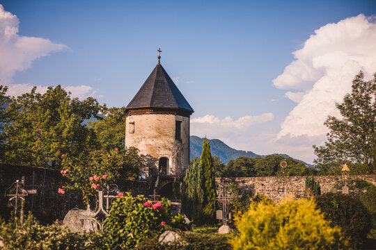 Friedhof unter bew&ouml;lktem Himmel mit mittelalterlichem Turm