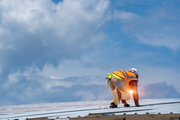 The Roofer technicians work and installing new roof structure on top roof of house,metal roof,fasteners corrugated sheets. © visoot