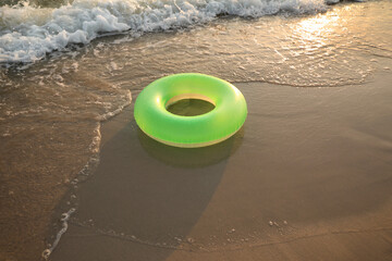 Green inflatable ring on sandy beach near sea, space for text