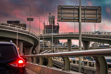Sunset in the city - driving tangled traffic-filled roads at rush hour under colorful sky -...