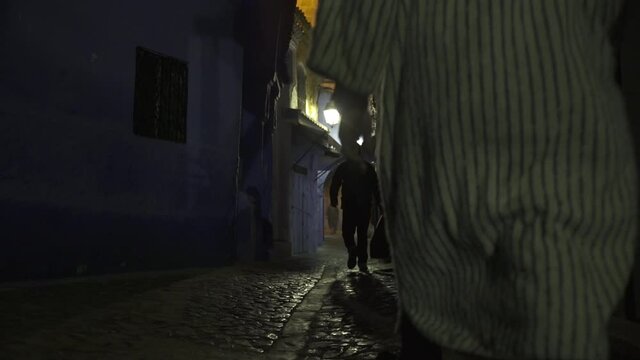 Persona caminando en la oscuridad de la noche en la ciudad de Chefchaouen en Marruecos
