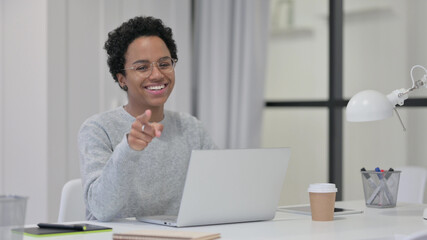 African Woman with Laptop Pointing at Camera 