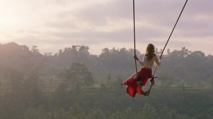 travel woman swinging over tropical rainforest at sunrise female tourist sitting on swing with scenic view enjoying freedom on vacation having fun holiday lifestyle slow motion - Powered by Adobe