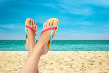 Woman wearing stylish flip flops resting on sandy beach and enjoying beautiful seascape, closeup - obrazy, fototapety, plakaty