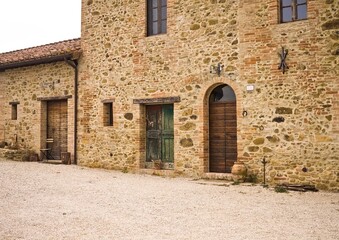 Fototapeta na wymiar The facade of a rural stone farmhouse with wooden doors and windows in the italian countryside (Tuscany, Italy, Europe)