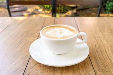 Latte coffee or cappuccino coffee in white cup with beautiful tree latte art on wooden table.