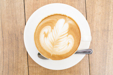 Top view of Latte coffee or cappuccino coffee in white cup with beautiful tree latte art on wooden table.