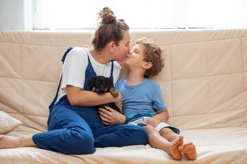A boy with mother and a little dog playing at home