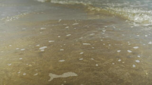 Movimientos de la marea en la orilla de la playa, peque&ntilde;as olas creando una capa de espumA