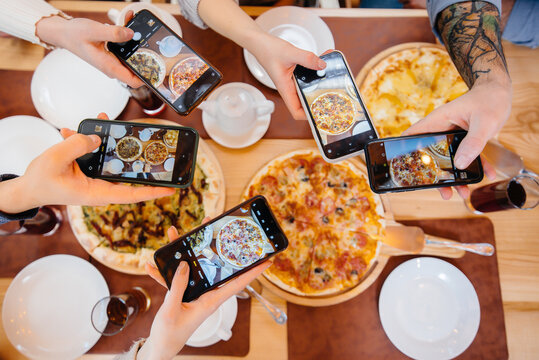 A group of friends takes a close-up photo of a delicious pizza for the blog, pizzeria.