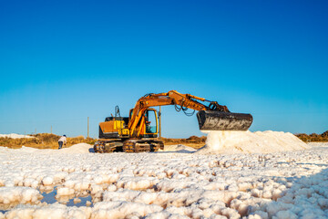 Sea salt harvest with yellow digger at salines in Faro, Portugal