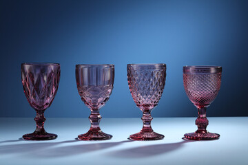 Four empty wine pink glasses color on a blue background